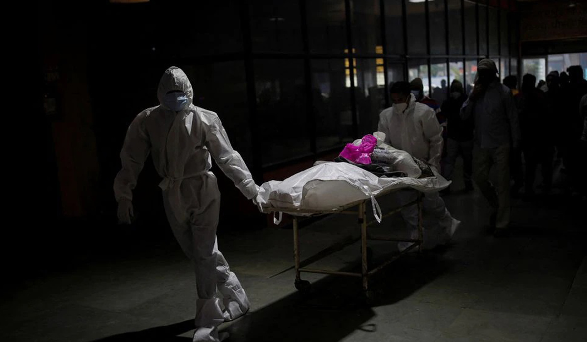 Health workers wearing personal protective equipment (PPE) carry the body
